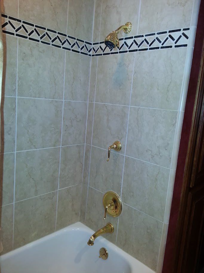 A bathroom with a bathtub and a shower with gold faucets