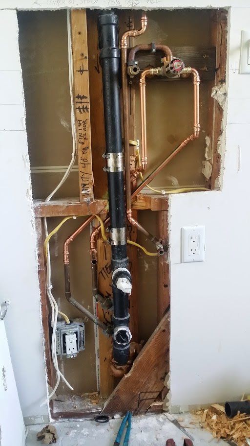 A plumbing pipe is being removed from a wall in a bathroom.