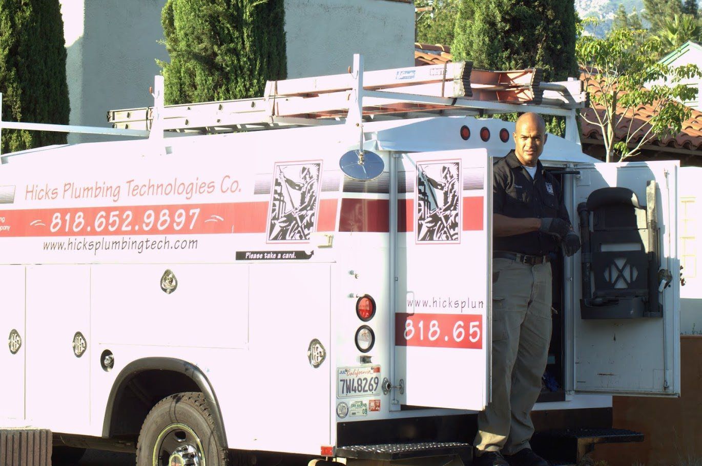 A man is standing in front of a plumbing truck
