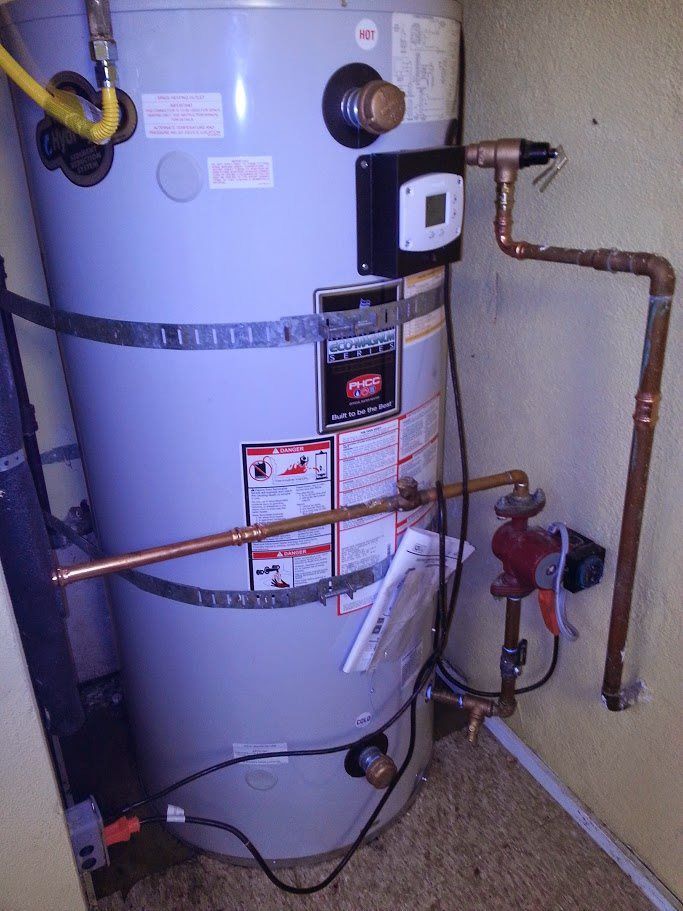 A water heater is sitting in a room next to a wall.