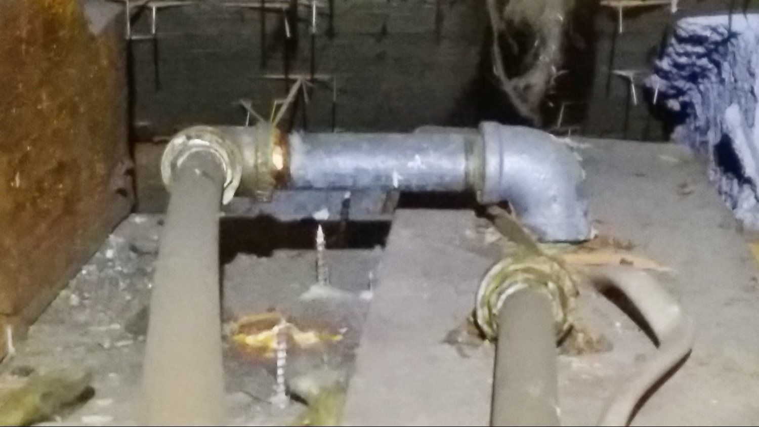A close up of a pipe in a room with a hose attached to it.