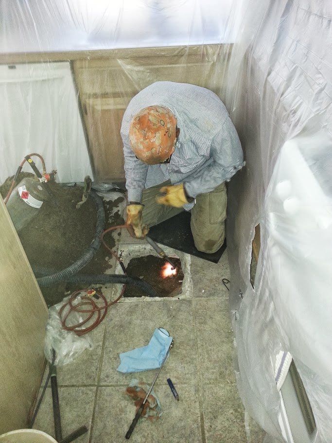 A man is working on a hole in the floor in a room.