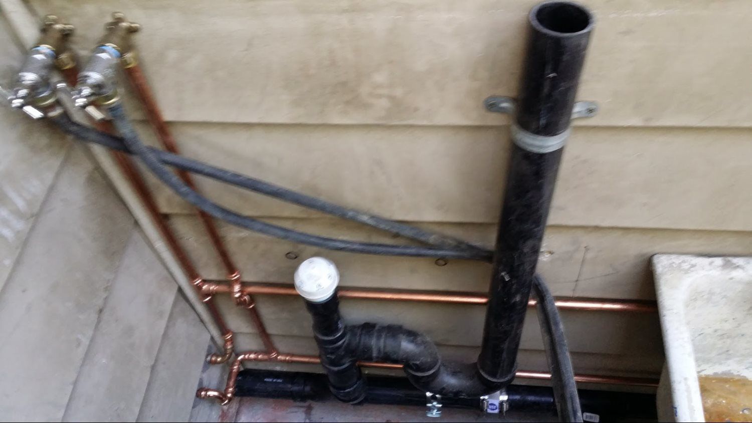 A bunch of pipes are connected to a wall next to a sink.