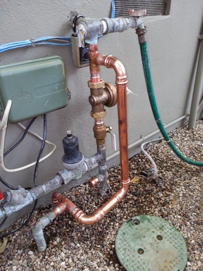 A copper pipe with a green hose attached to it