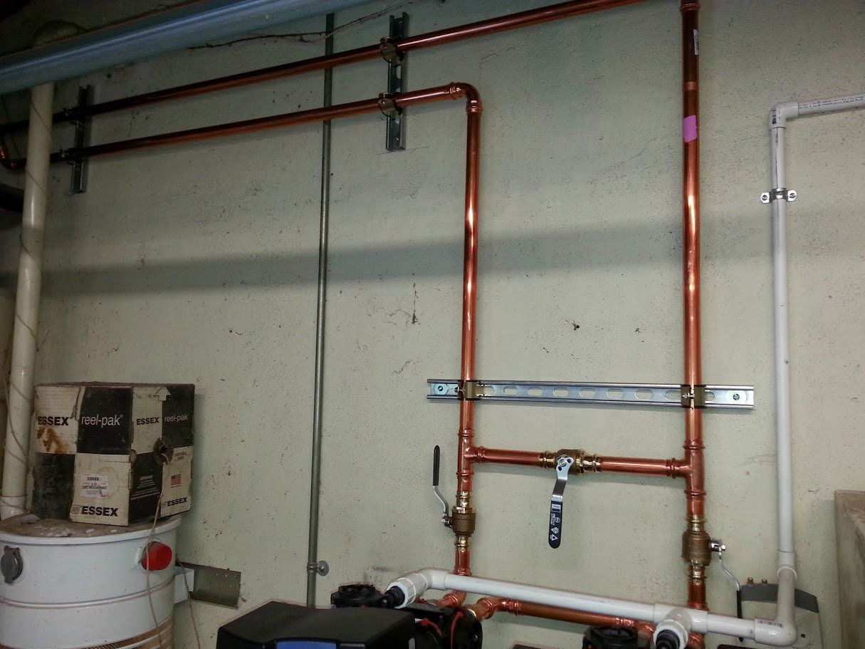 Copper pipes are hanging on a wall in a room