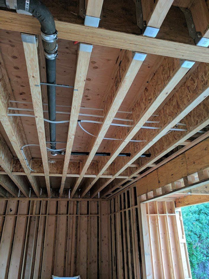 A pipe is hanging from the ceiling of a house under construction.
