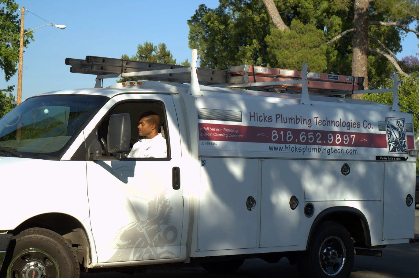A man is driving a white plumbing truck