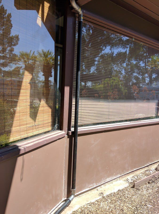 A window with blinds on it is on the side of a building.