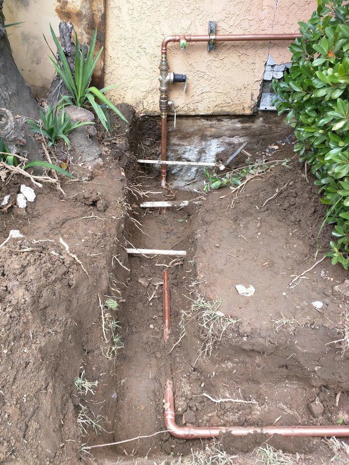 A copper pipe is being installed in a hole in the ground.