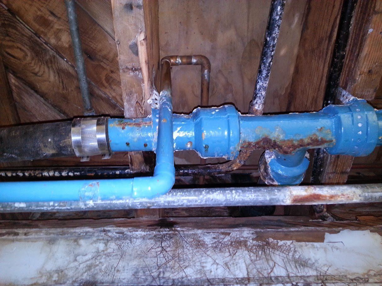 A blue pipe is connected to a wooden wall.