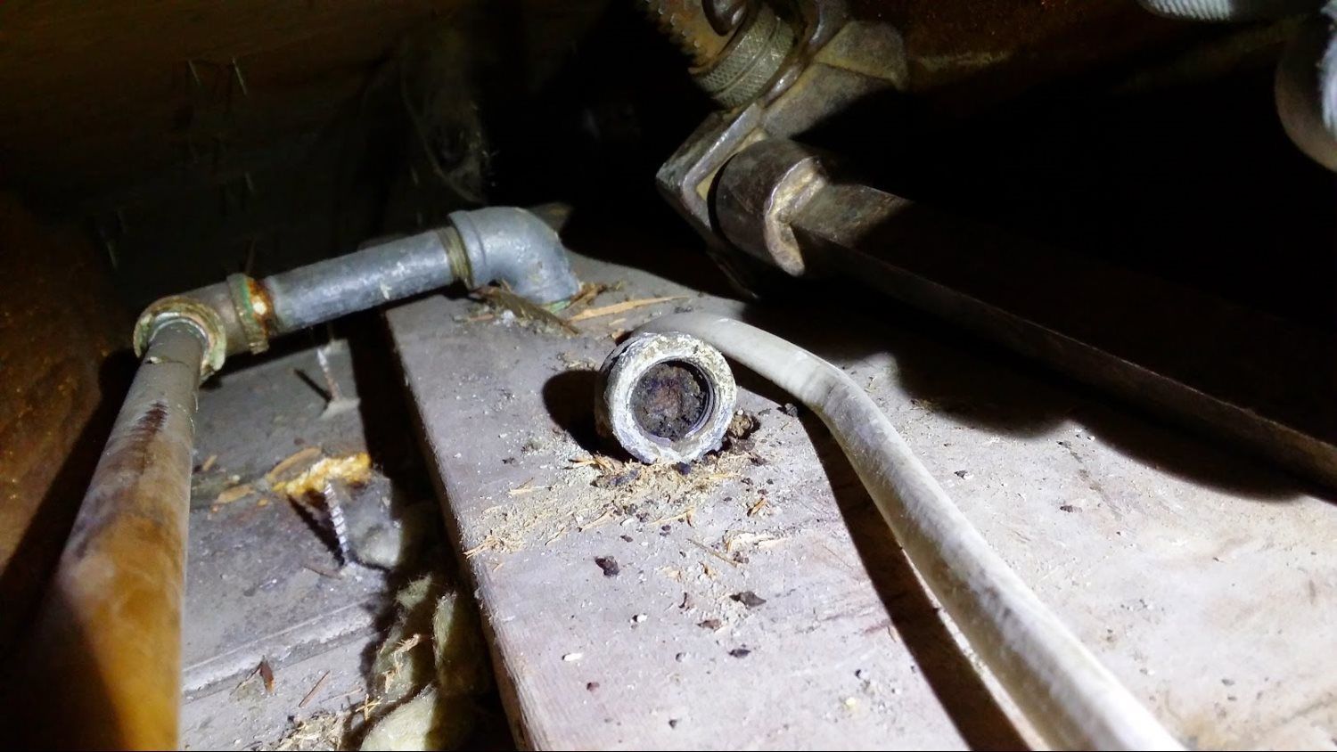 A pipe with a hole in it is sitting on top of a wooden table.