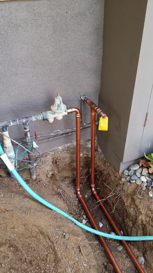 Copper pipes are being installed in a hole in the ground.