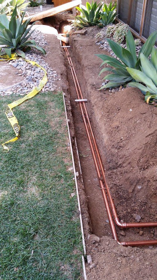 A copper pipe is being installed in a garden.