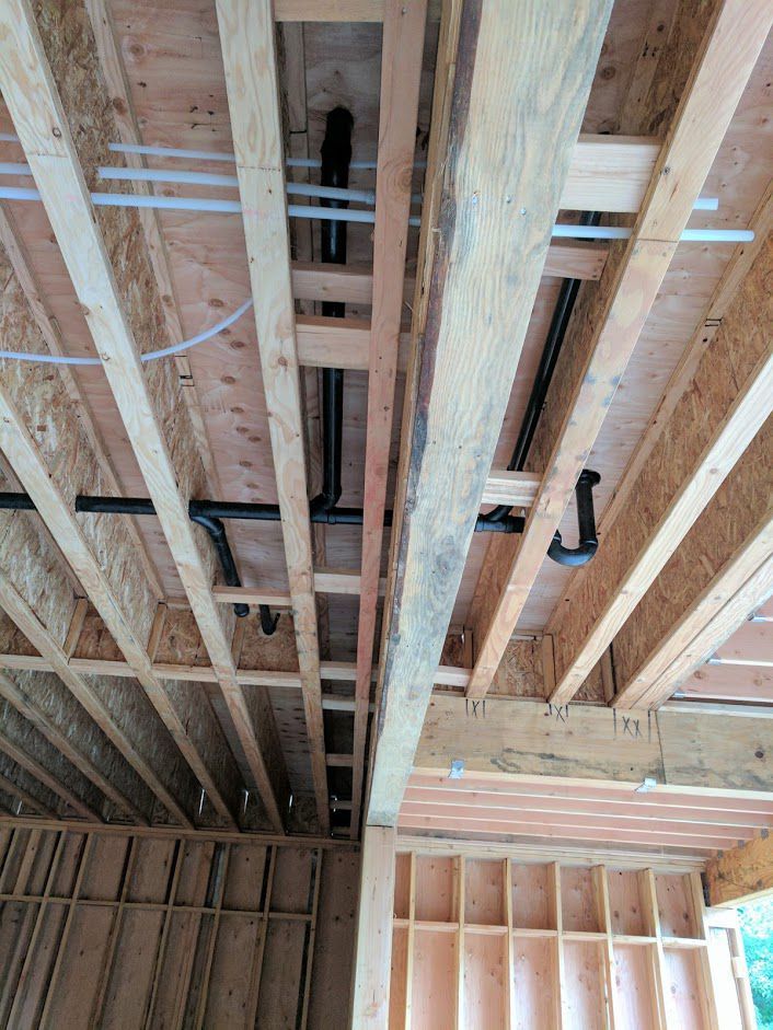 The ceiling of a house under construction with pipes coming out of it.