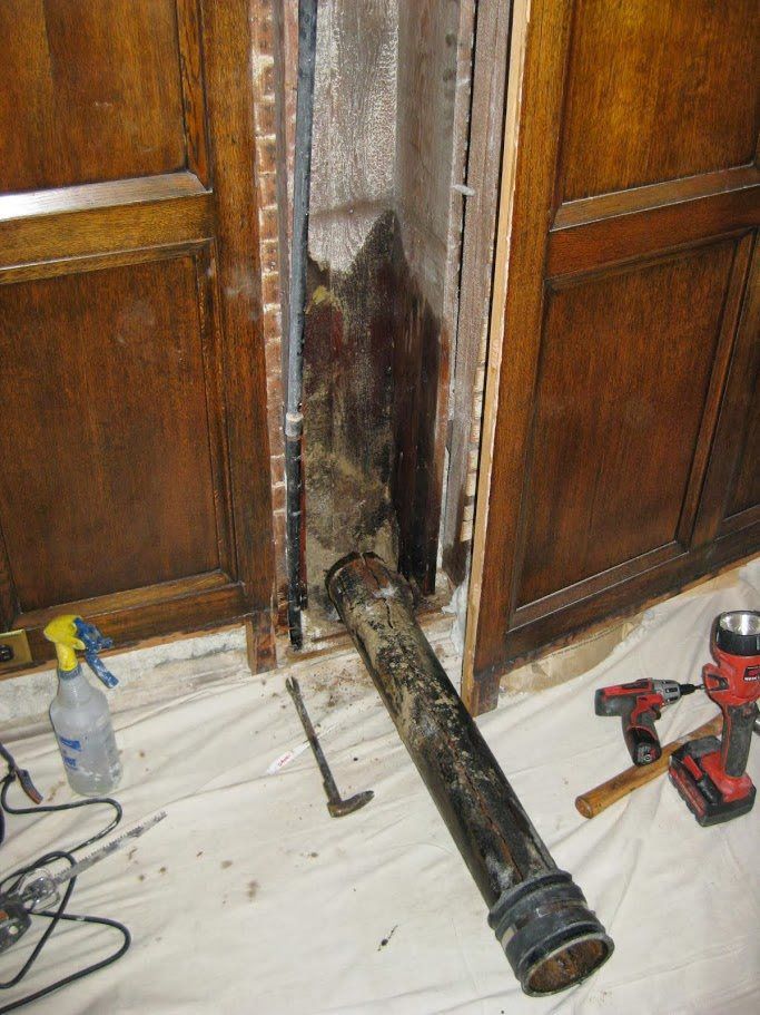 A pipe is laying on the floor next to a spray bottle and a drill.