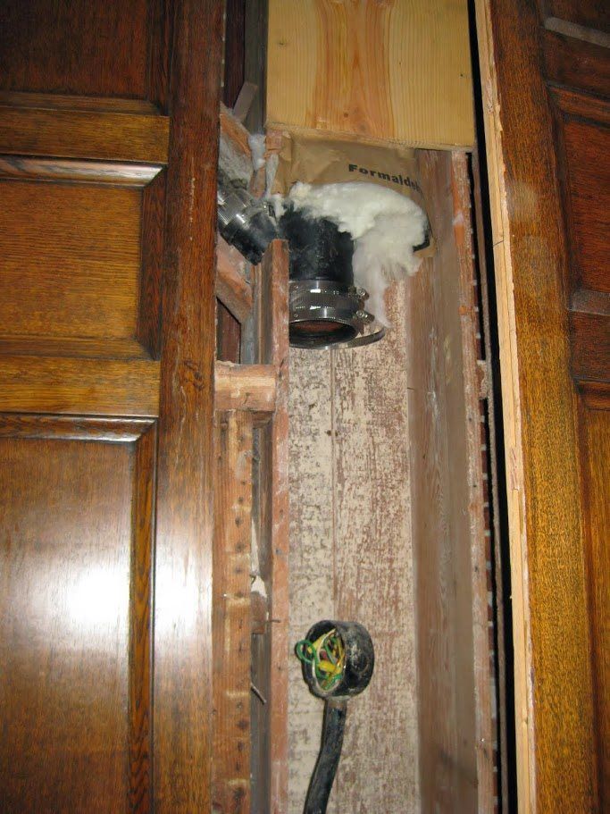 A hole in a wooden wall with a hose coming out of it