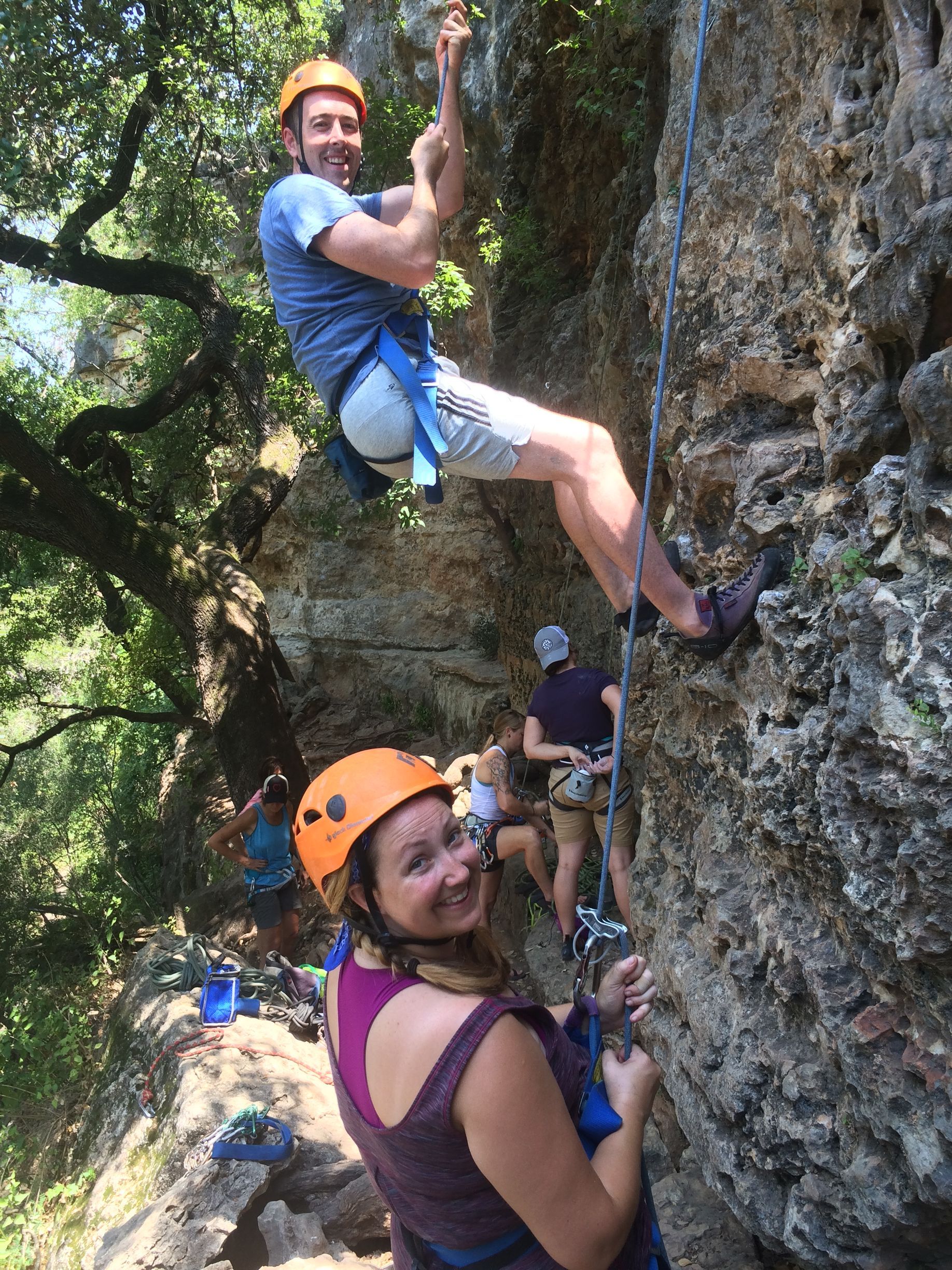 A man and a woman are climbing up a rock wall.