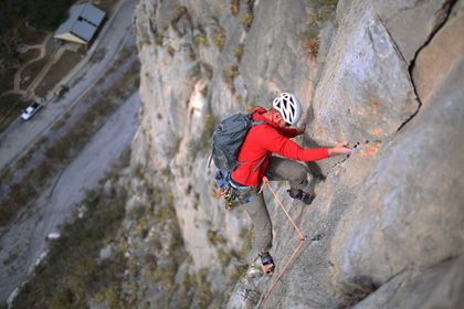 A person is climbing up a rock wall with a helmet on.