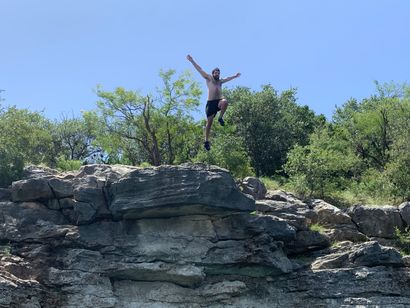 A man is jumping off a cliff into a body of water.