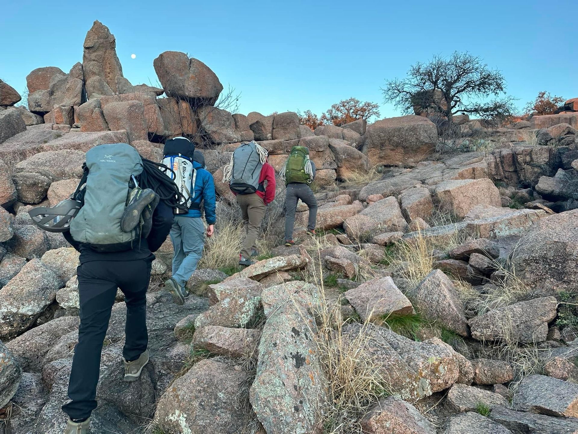 A group of people with backpacks are walking through a rocky area.