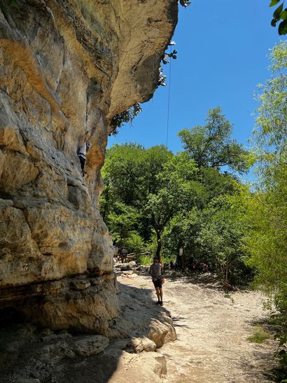 A person is walking down a dirt path next to a rock wall.