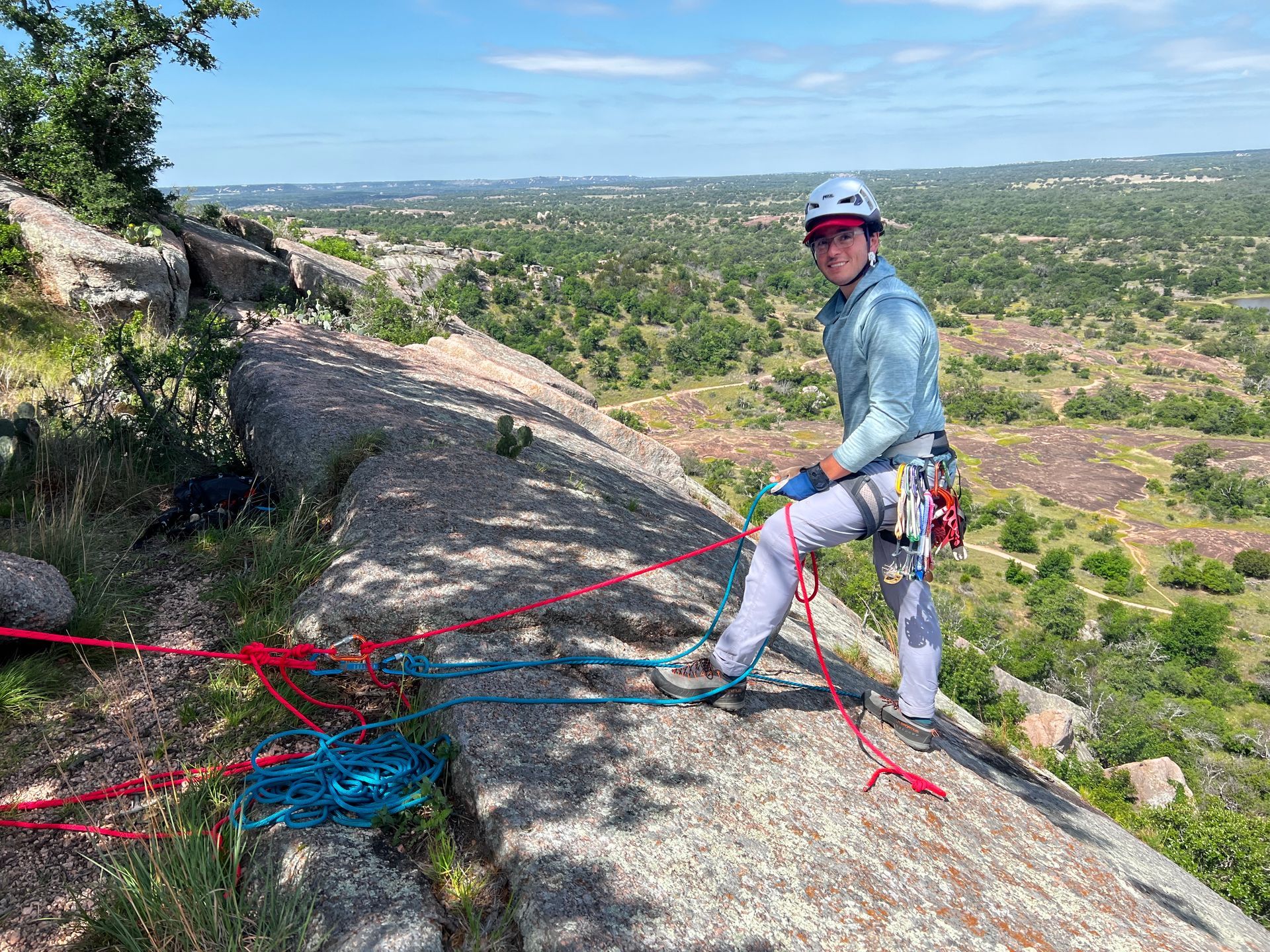 A man is standing on top of a rock holding a rope.