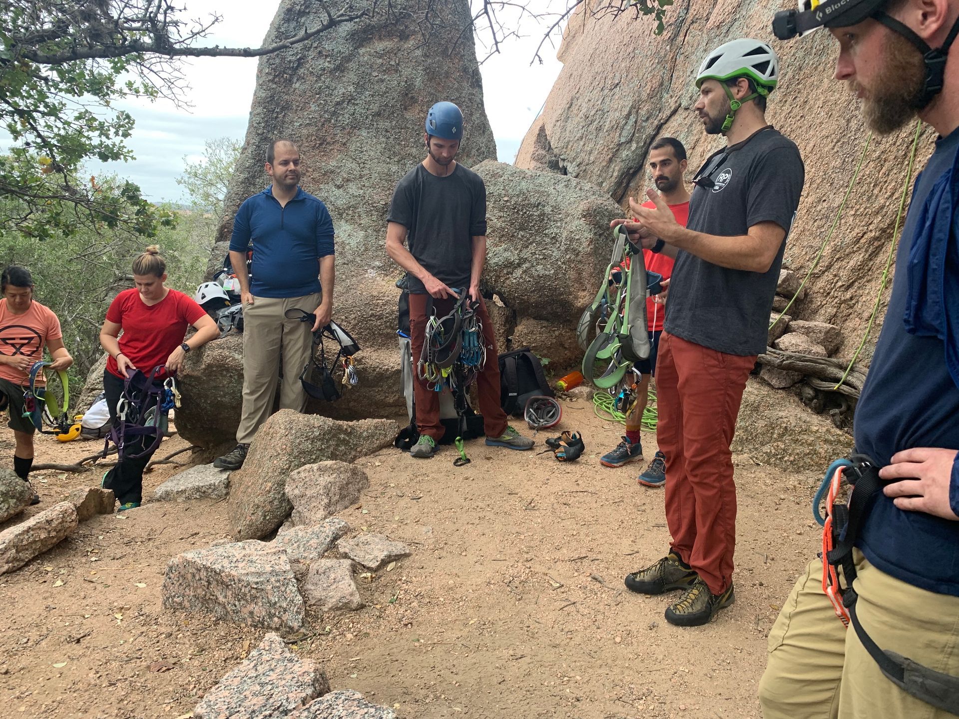 A group of people are standing around a large rock.