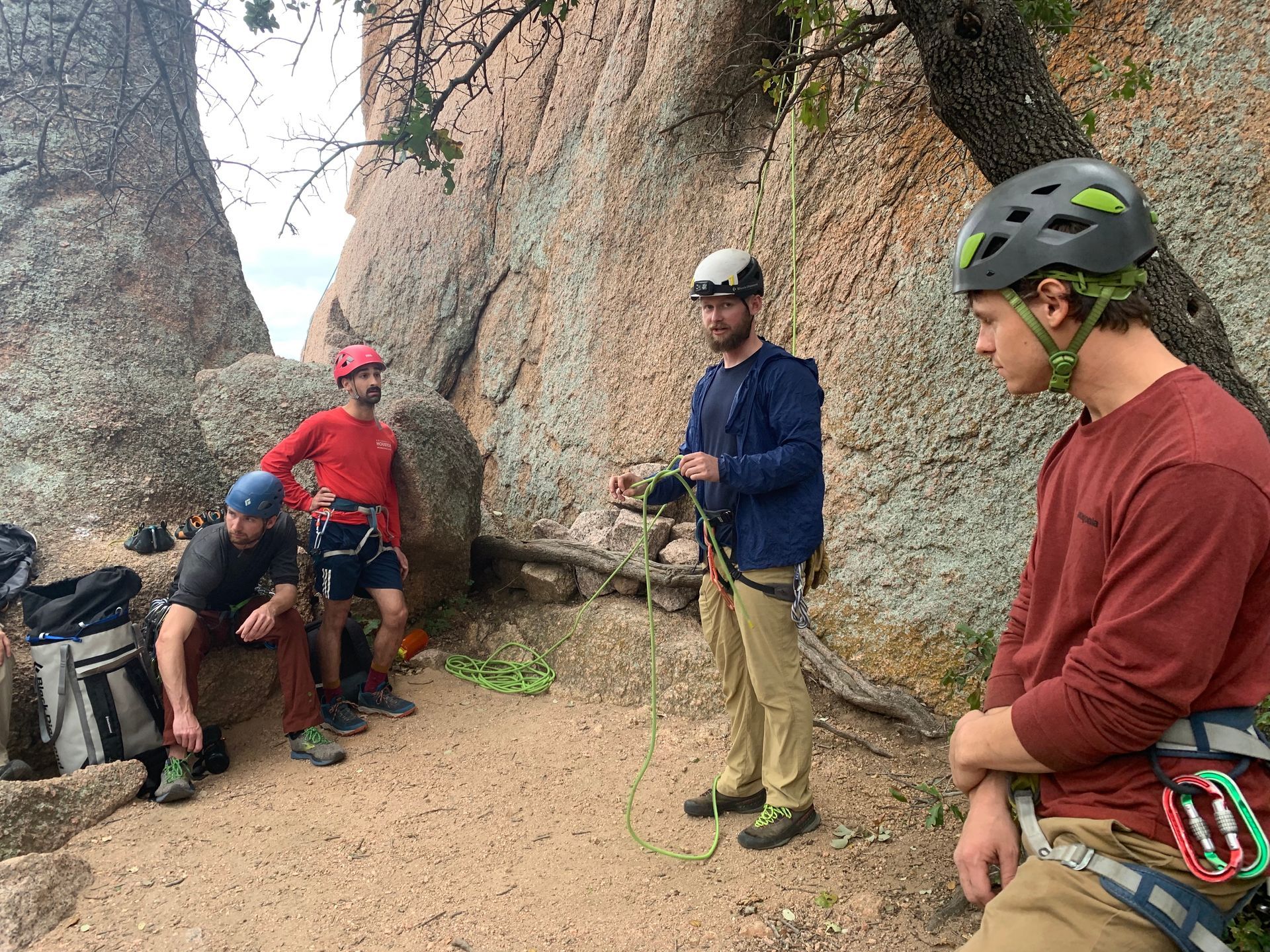 A group of men are standing in front of a rock wall.