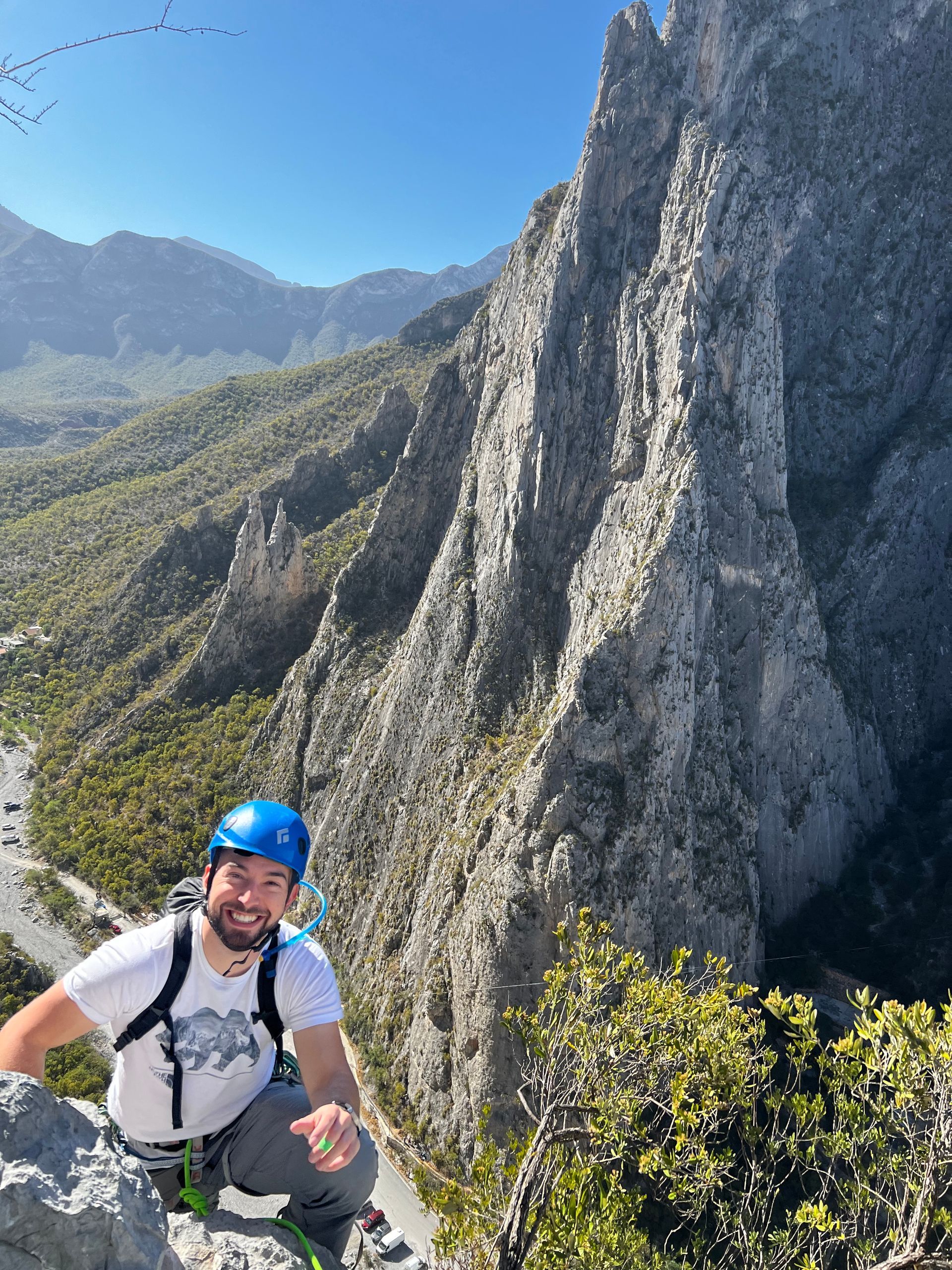 A man wearing a helmet is standing on top of a mountain.