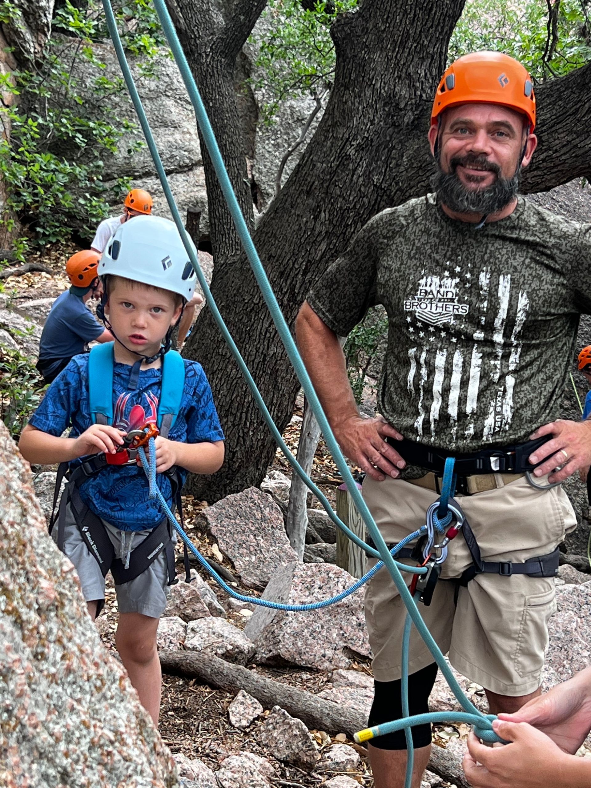 A man and a boy are standing next to each other on a rock climbing trail.
