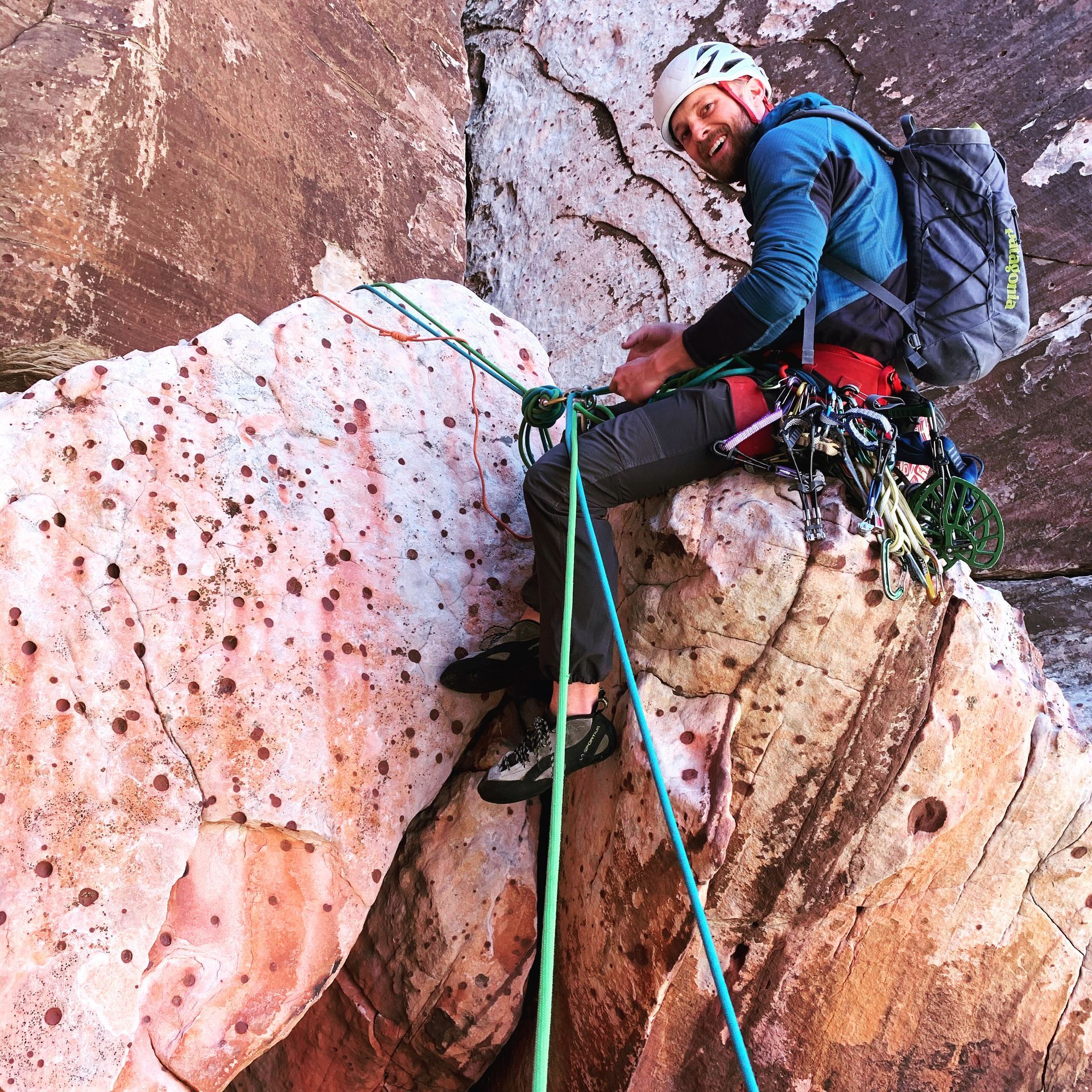 A man with a backpack is sitting on top of a rock.