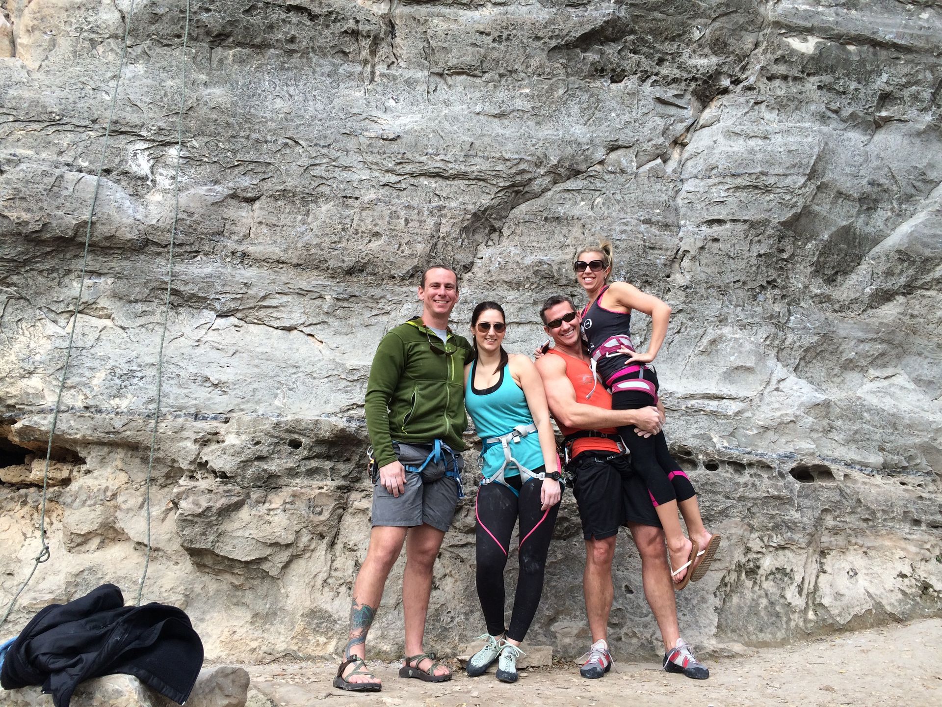 A group of people are posing for a picture in front of a rock wall.