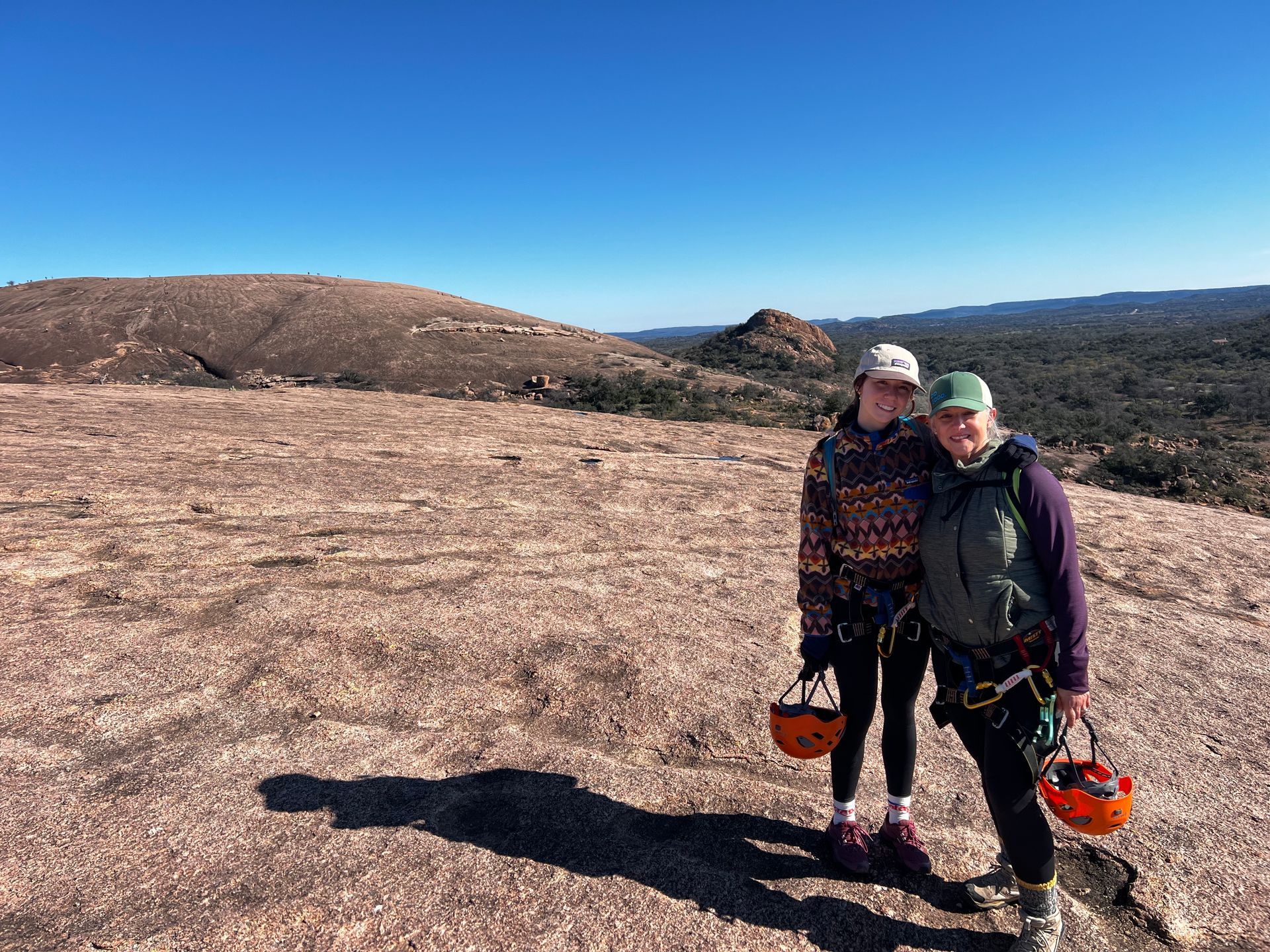 Two people are standing on top of a rocky hill.