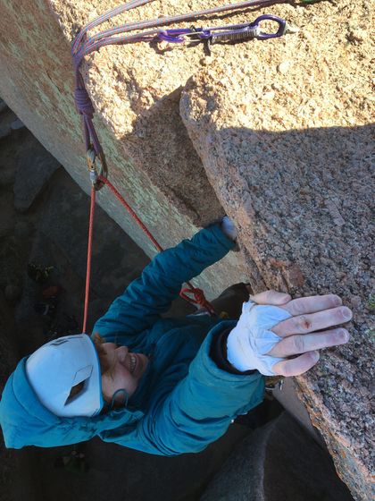 A person wearing a mask is climbing a rock wall.