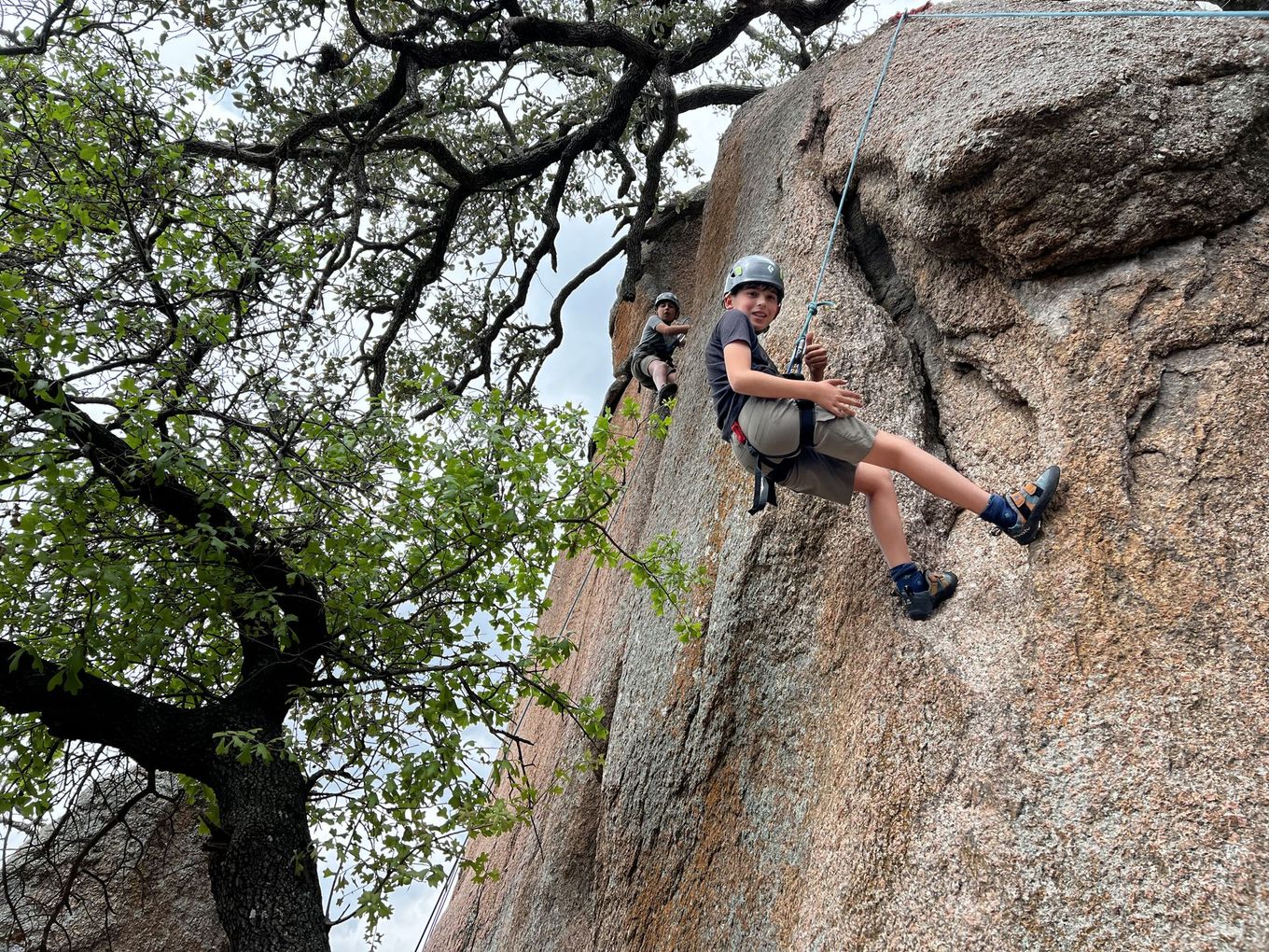 A young boy is climbing up a rock wall.