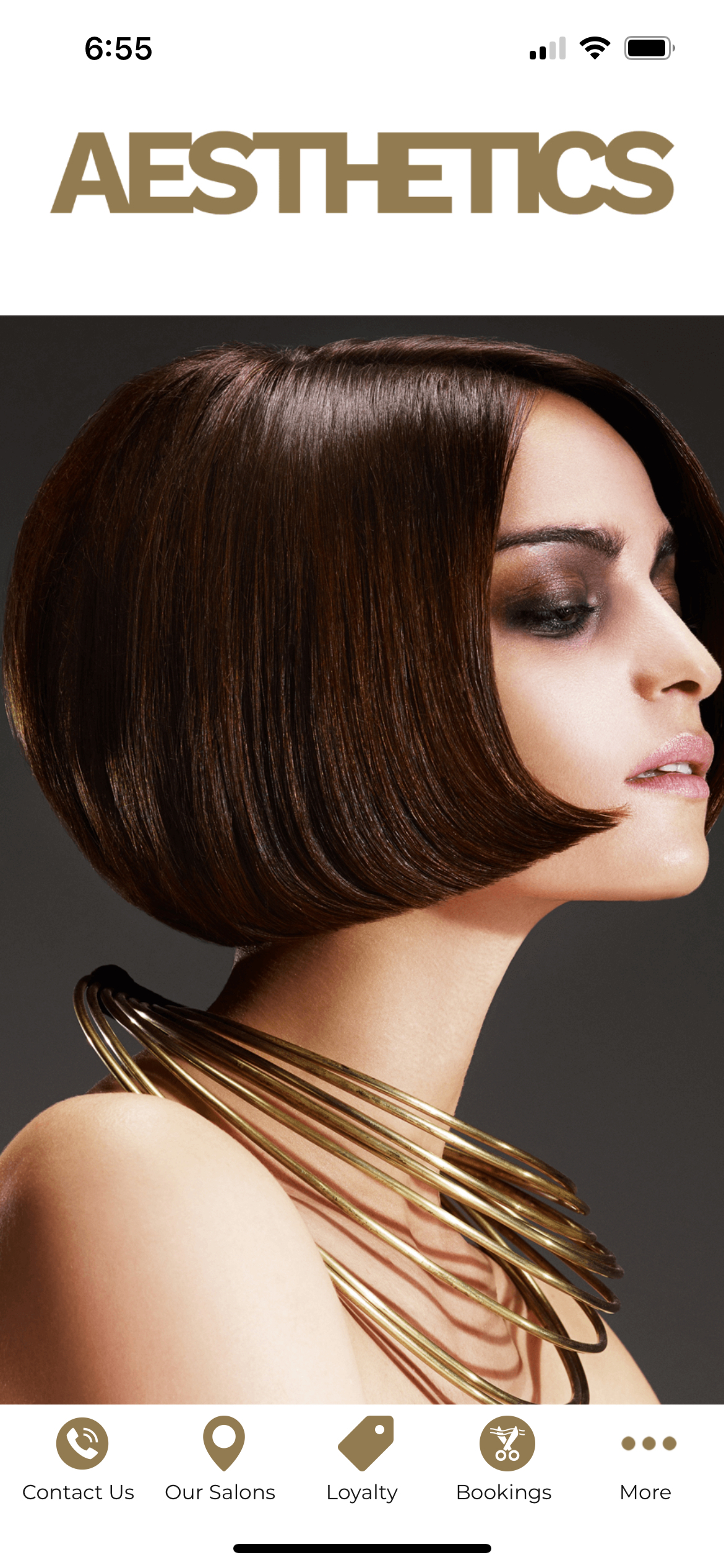 A woman with short brown hair is wearing a gold necklace.