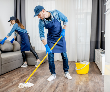 A man and a woman are cleaning the floor in a living room.