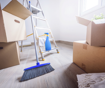 A room filled with boxes , a ladder , a broom and a spray bottle.