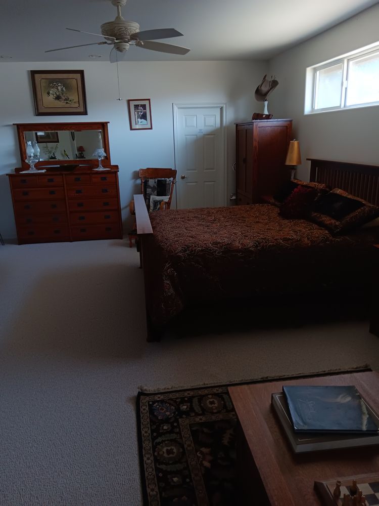 A bedroom with a bed , dresser , mirror and ceiling fan.