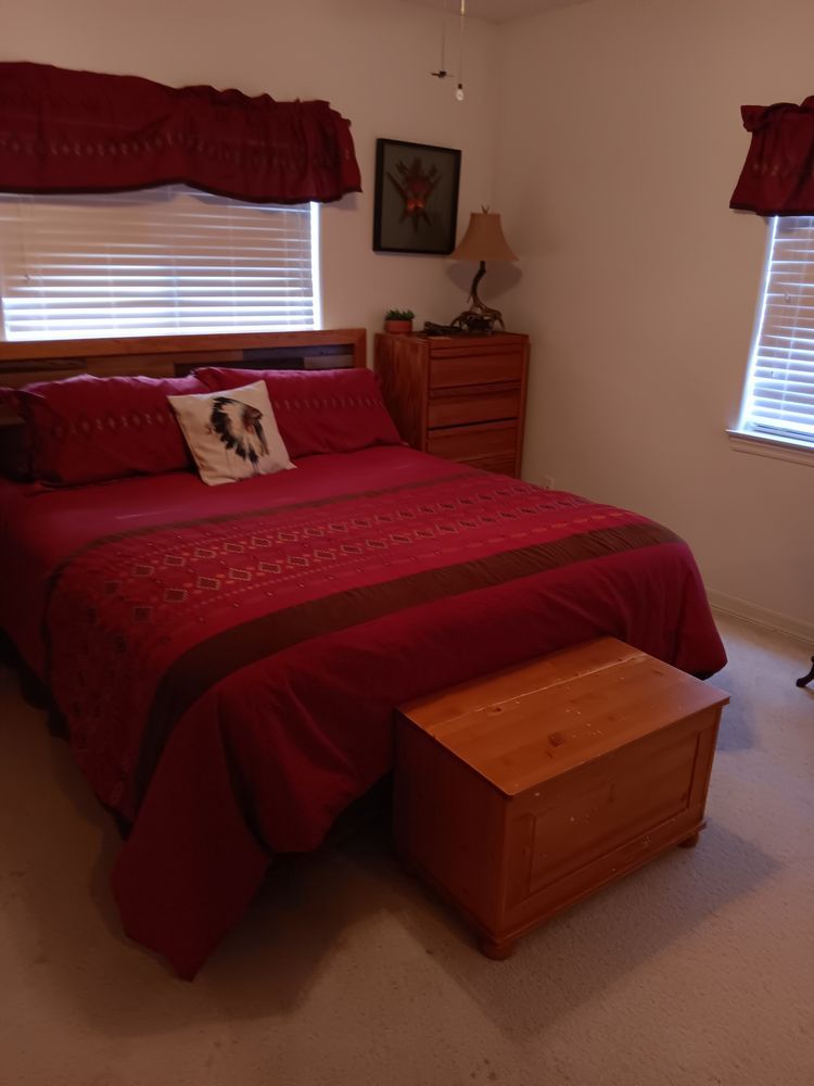 A bedroom with a bed , dresser , nightstand and window.