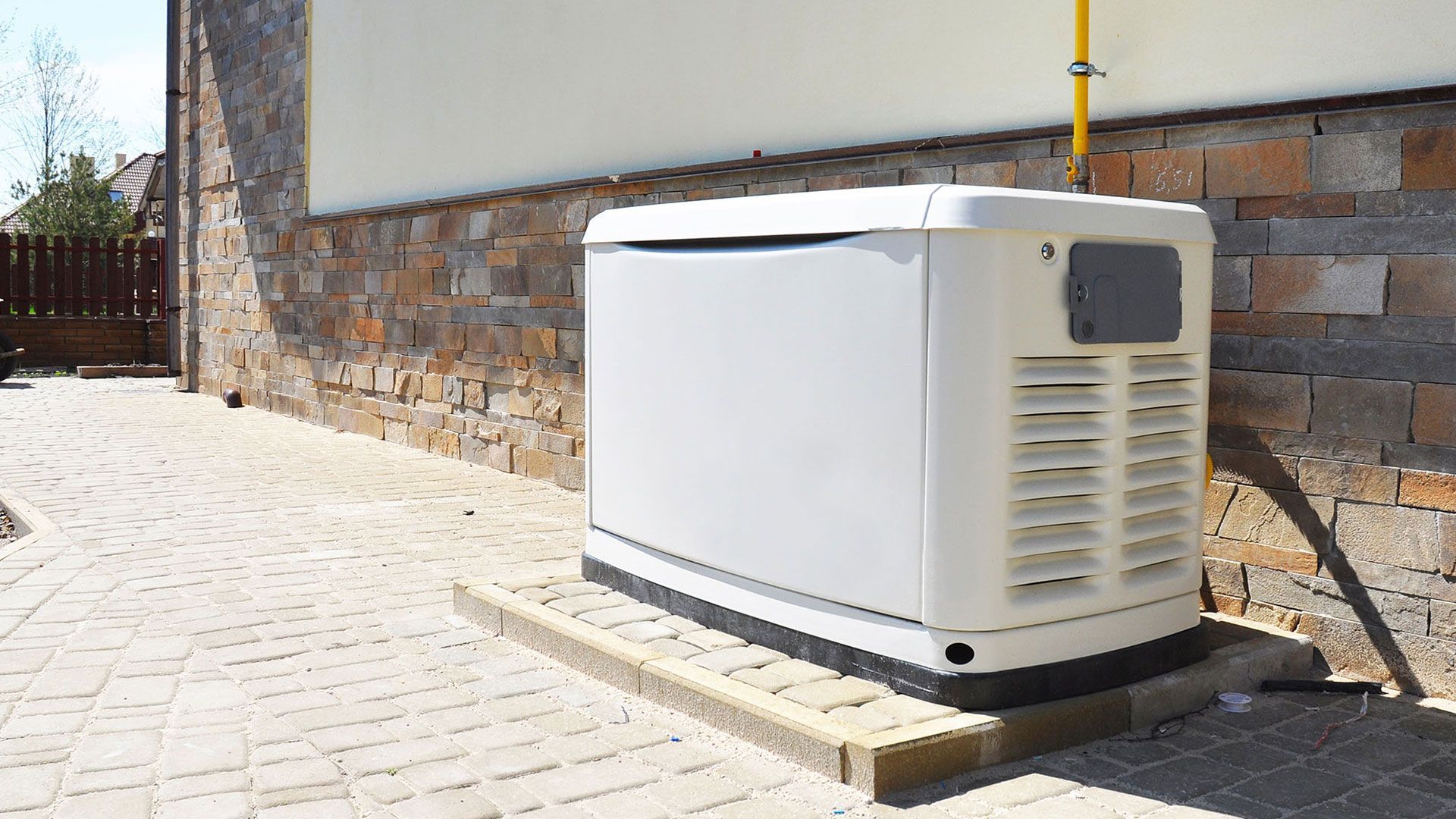 A white generator is sitting on the side of a building.