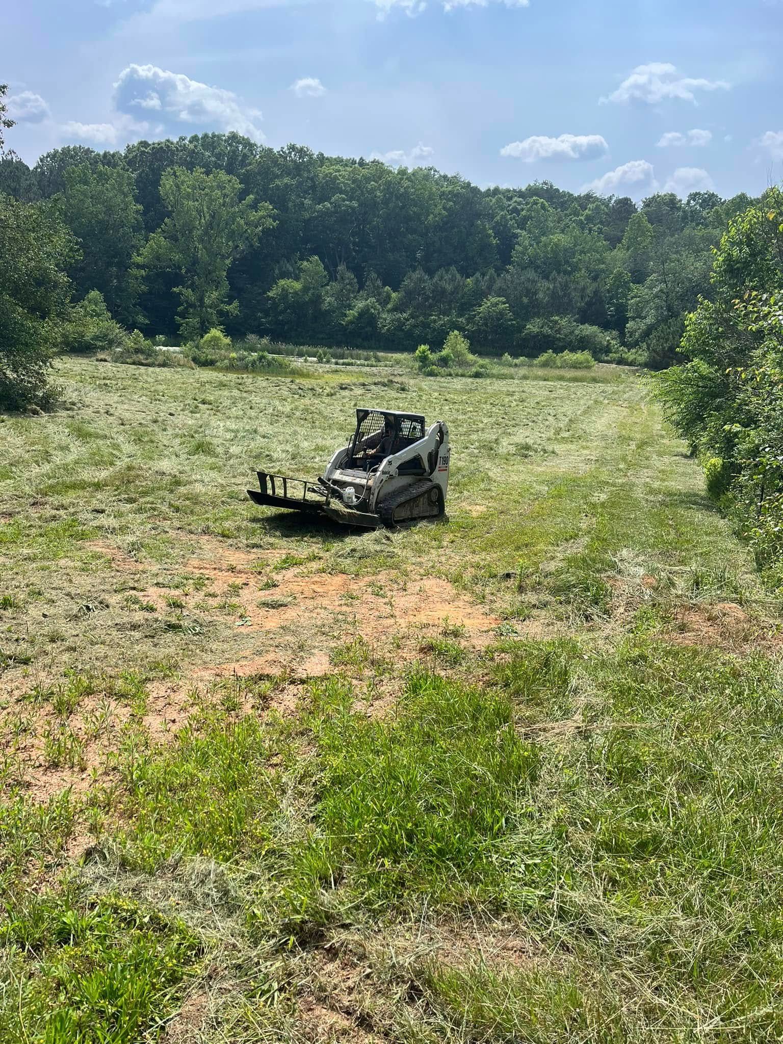 A black off-road vehicle in a grassy field with trees and blue sky in the background.