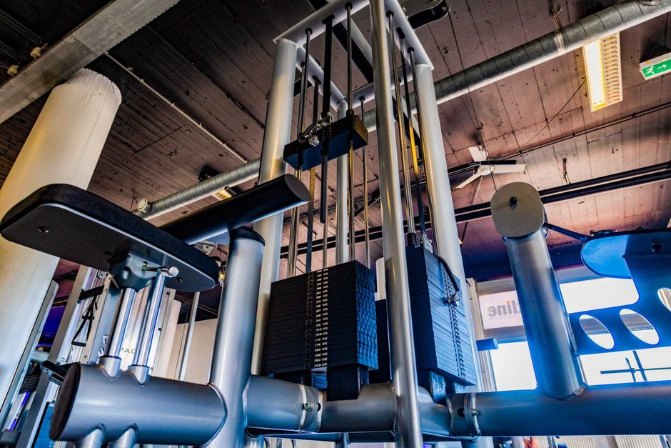 een sportschool met veel fitnessapparatuur die aan het plafond hangt.