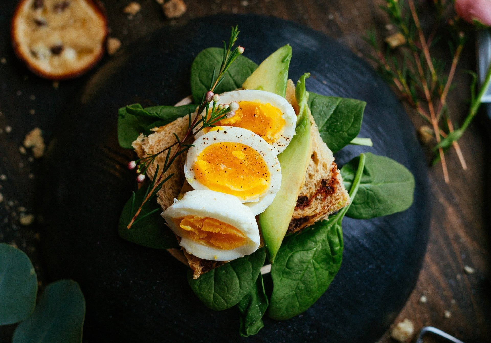 een close-up van een bord eten met hardgekookte eieren, spinazie en avocado.