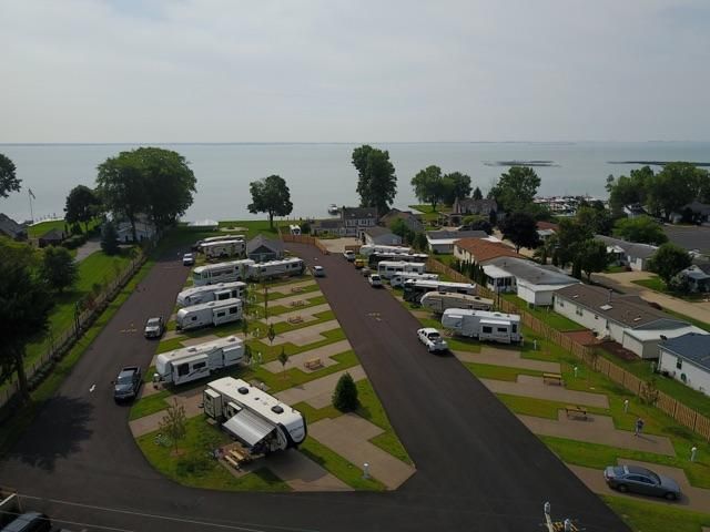 Rv park beside a lake, with rows of white trailers and cars on paved lots.