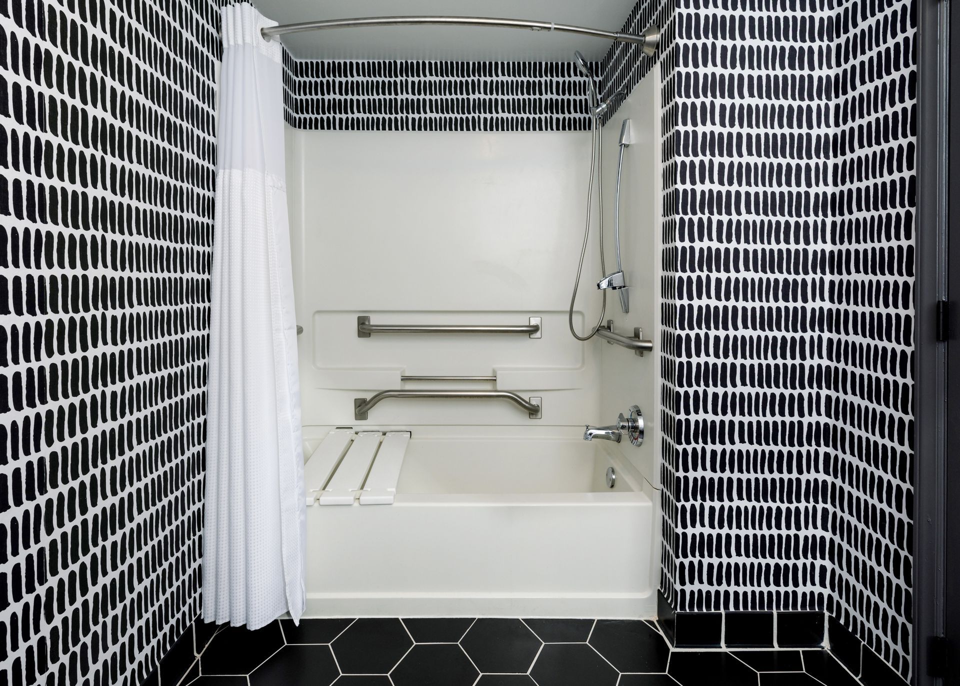 A bathroom with black and white tiles and a bathtub.