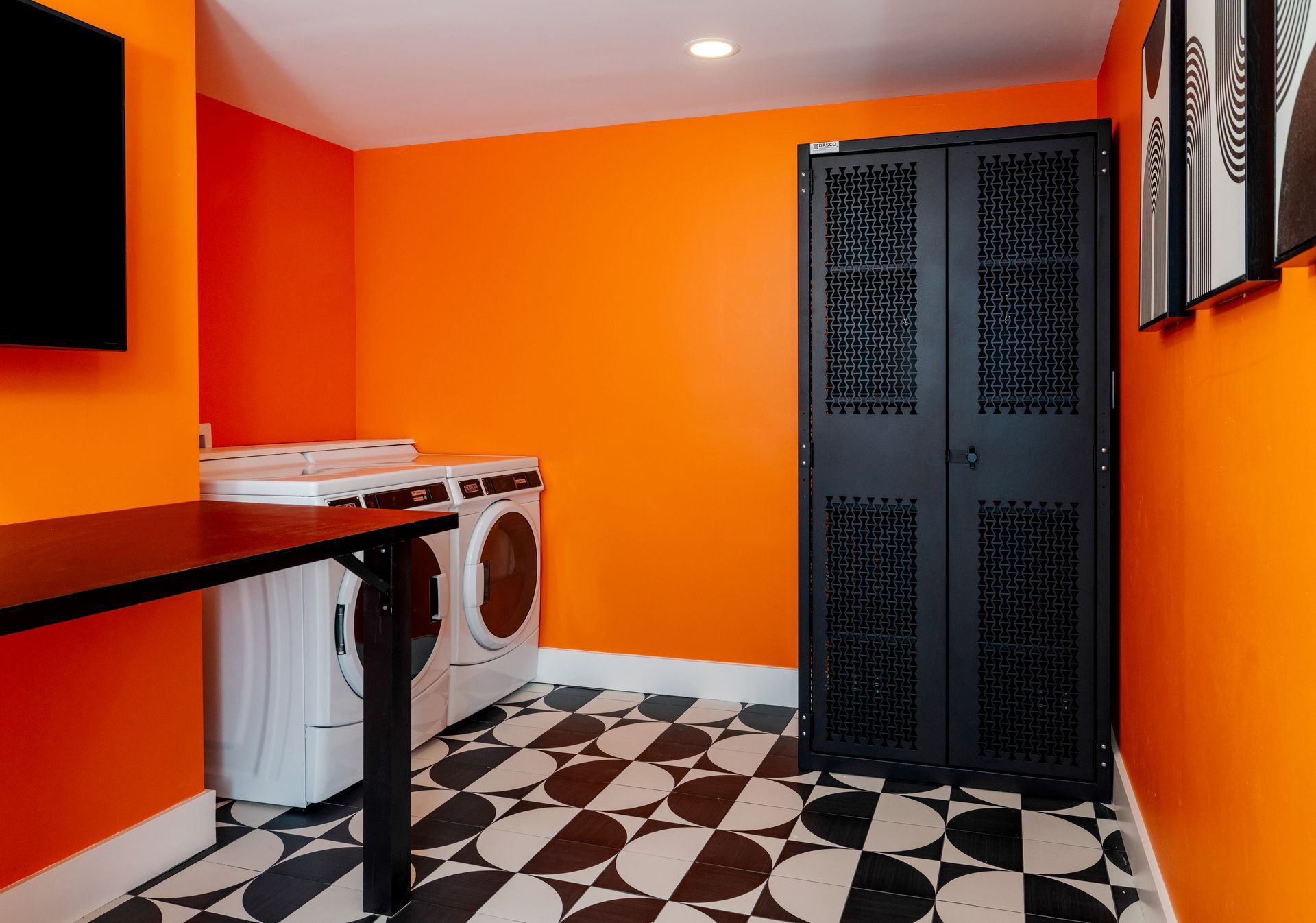 A laundry room with orange walls and a black and white checkered floor.