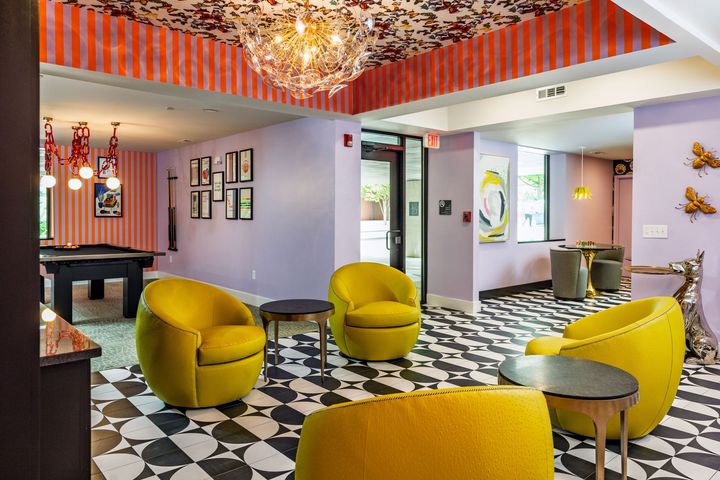 A living room with yellow chairs and a pool table.