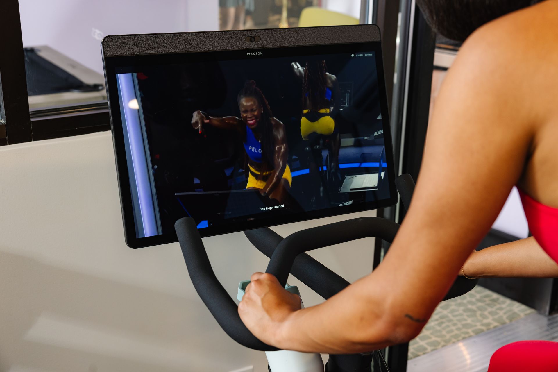 A woman is riding an exercise bike with a tablet attached to it.