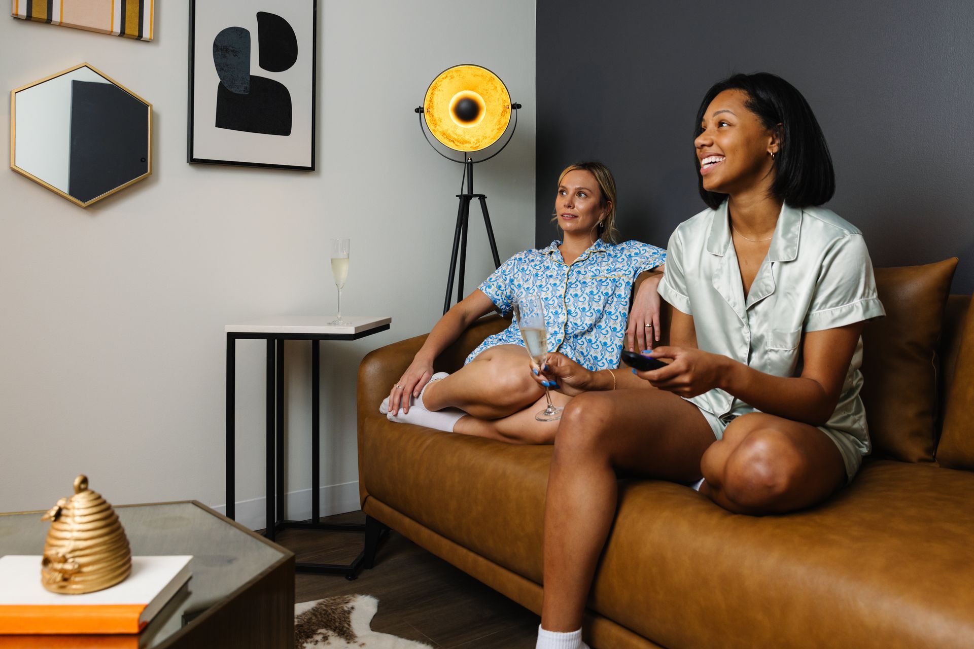 Two women are sitting on a couch in a living room.
